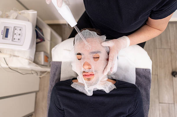 istock Aesthetician Using High-Frequency Wand on Man’s Face During Facial Treatment 2206709212