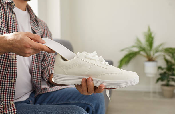 istock Man puts new orthotic insole with arch support inside comfortable orthopedic shoe 2206716736