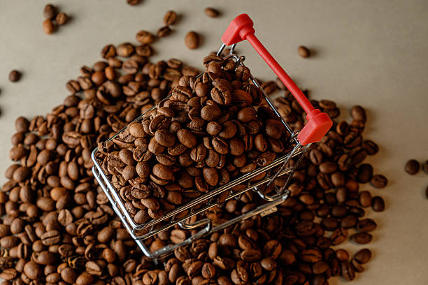 istock Coffee beans fill a miniature shopping cart on a rustic background 2206717522