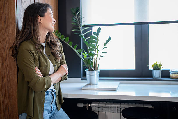 istock Young woman relaxing in modern kitchen, looking out window 2206717862