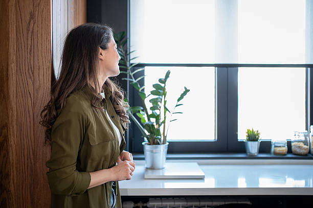 istock Young woman relaxing and looking out the window in a modern kitchen 2206717864
