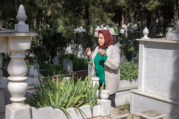 Muslim woman praying in cemetery on Eid eve