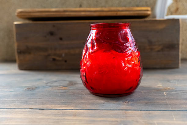 Bright red candle in an intricately designed glass holder placed on a rustic wooden surface enhancing a warm ambiance