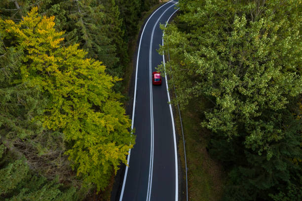 istock Red Car Driving on a Scenic Forested Road During Autumn 2206725241