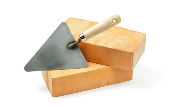 istock Masonry Trowel Resting on Two Orange Bricks Isolated on White Background 2206727530