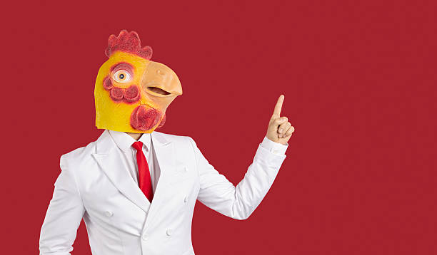 istock Crazy guy in suit and chicken mask pointing finger to side at red copy space background 2206733844