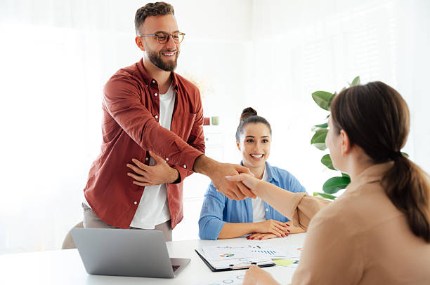 istock Successful agreement. The colleagues are shaking hands while smiling at each other. Group of business partners working together in a modern office on a project, make a good deal, planning cooperation 2206739967