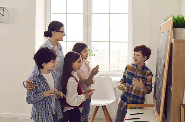 istock Pupil answering at blackboard front of teacher and classmate 2206745580