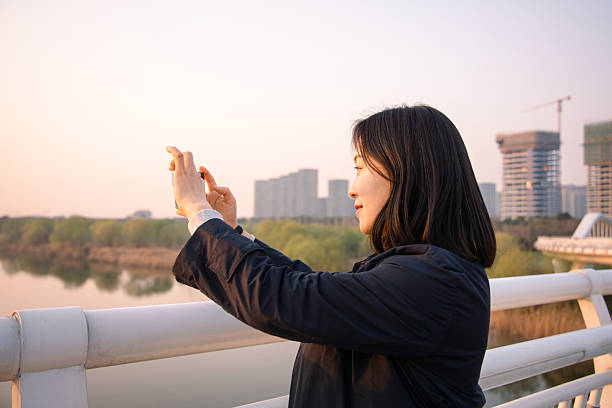 istock asian female take picture with smart phone in city 2206745607