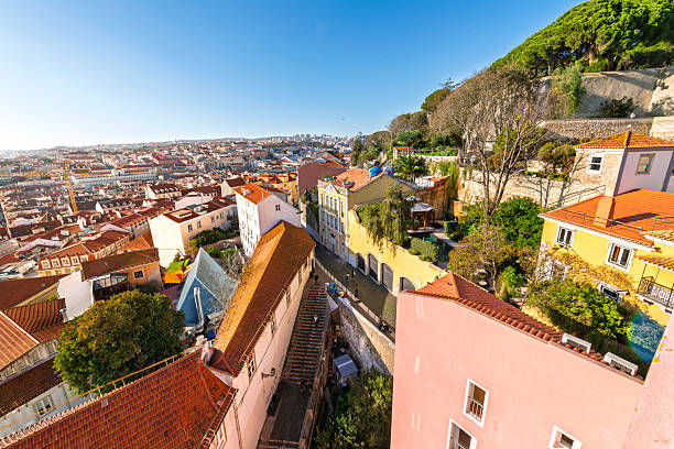 High angle rooftop view from the medieval Alfama district of the Saint George castle grounds and city of Lisbon, Portugal, along the Tagus River in Southern Europe.