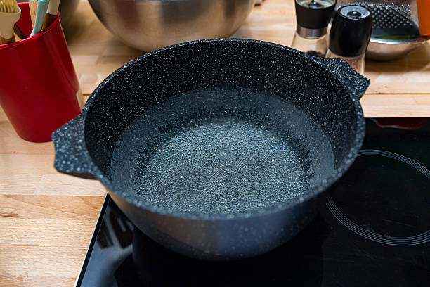 istock Black pot with boiling water on stove. 2206752159