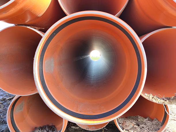istock Stack of large orange industrial pipes with sunlight at tunnel end 2206757510