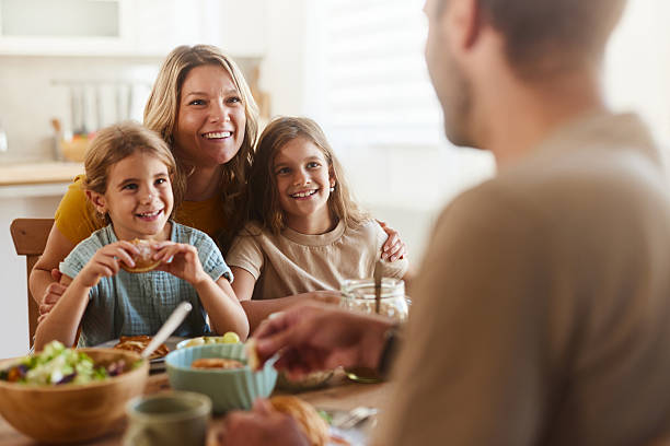 istock Happy mother and daughters talking to father during breakfast at dining table. 2206786174
