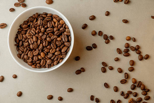 istock Exquisite coffee beans spill from white bowl onto rustic surface 2206787051