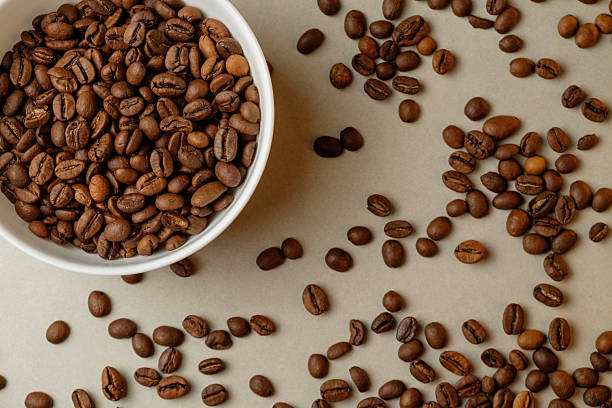 istock Perfectly roasted coffee beans scattered around a charming bowl 2206787055