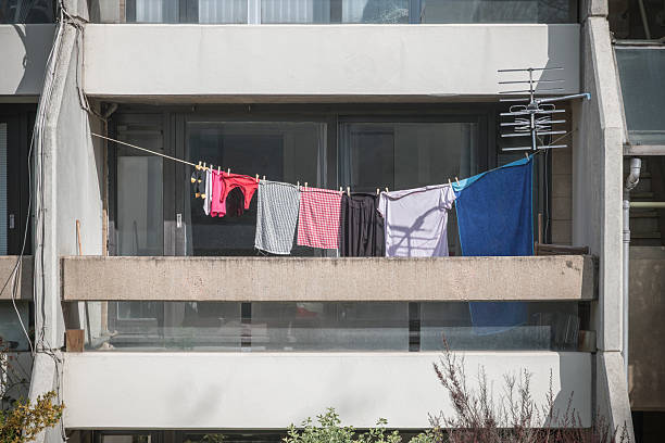 A balcony in an apartment  featuring a clothesline with colourful laundry drying in the sunlight, on Whittington Estate in Camden, London, England