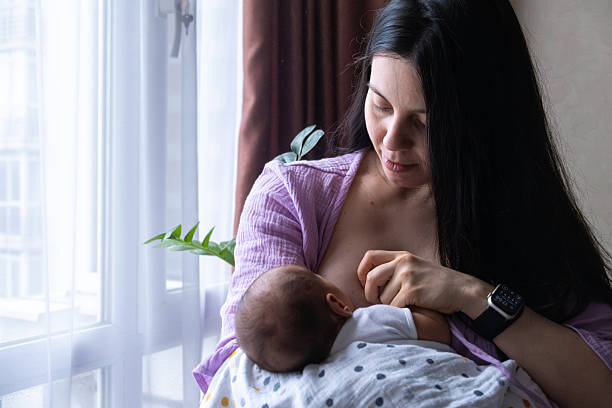 istock Mother Breastfeeding Baby by Window 2206790495