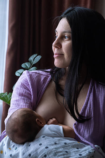 istock Mother Breastfeeding Baby by Window 2206790499