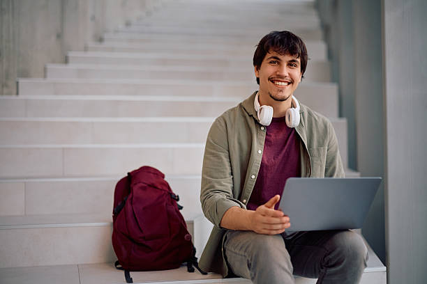istock Happy college student using laptop in a hallway and looking at camera. 2206790808