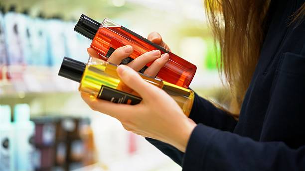 istock A female customer compares two shampoos reads the label examines the ingredients 2206793705