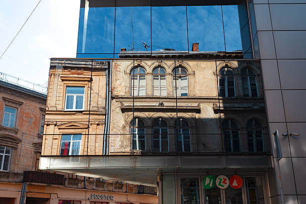 Lviv, Ukraine - Mar. 22, 2025: Modern glass architecture beautifully reflects the intricate details of historical buildings in Lviv during daylight, creating a stunning juxtaposition.