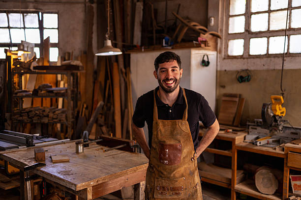 istock Smiling craftsman working in a sustainable wood workshop with tools and materials.He is looking at the camera 2206795708