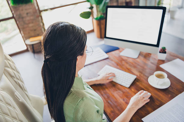 istock Brunette female working in modern office setting with daylight streaming, wearing elegant blouse, focused on task 2206797904