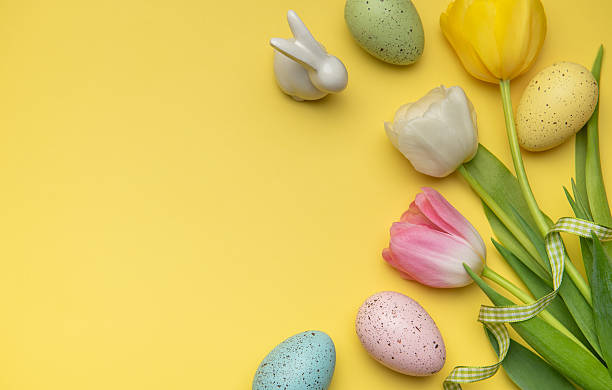 istock Easter eggs and tulips forming a frame on a yellow background 2206801984