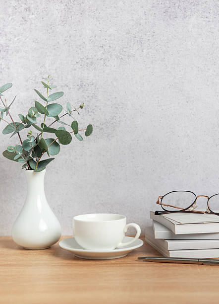 istock Eucalyptus branches, coffee cup, books and eyeglasses resting on wooden desk 2206802420