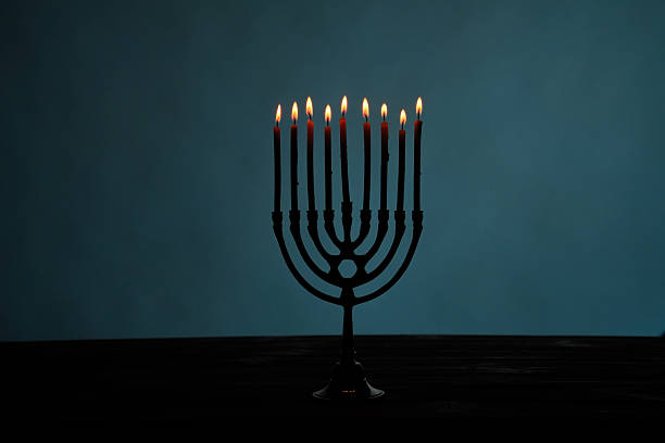 A beautifully lit menorah with nine candles, symbolizing the Jewish festival of Hanukkah, against a dark background.