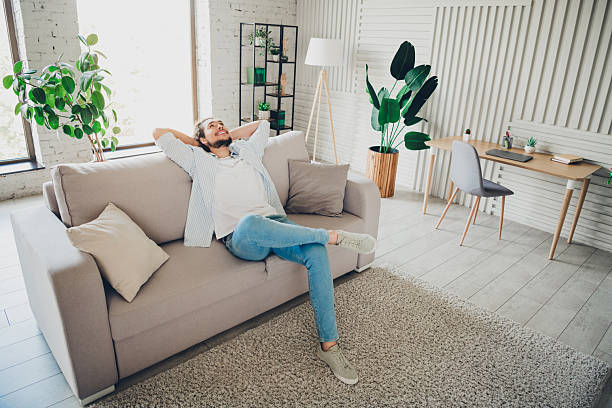 istock Young man relaxing on a sofa in a modern, light-filled living room with cozy decor, enjoying a peaceful moment 2206803164