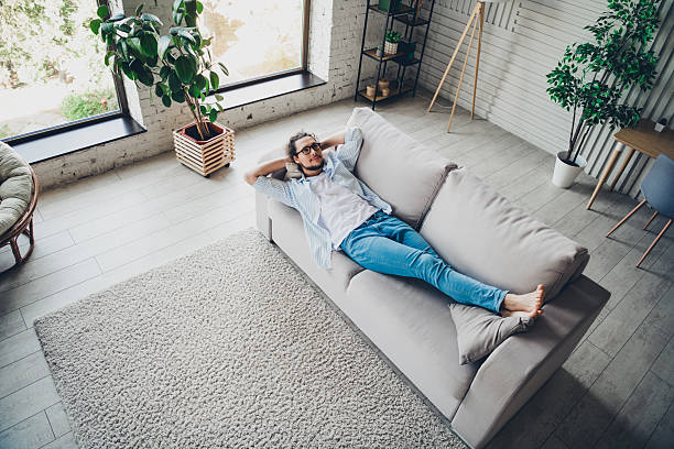 istock Young man relaxing on a sofa in a modern living room interior with natural daylight 2206803205