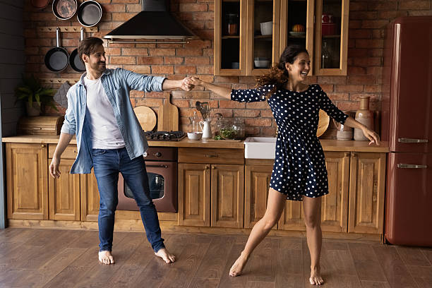 istock Happy millennial couple holding hands, dancing in cozy kitchen 2206803784