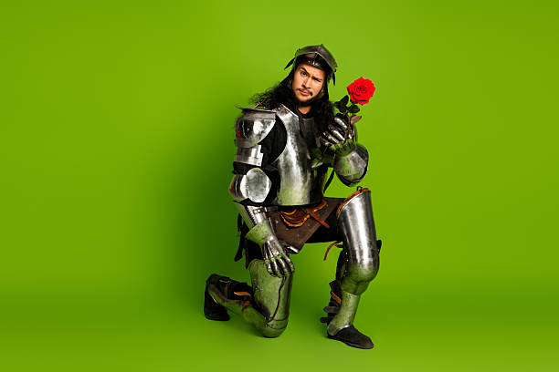 istock Medieval knight with rose in armor posing on vibrant green background 2206804263