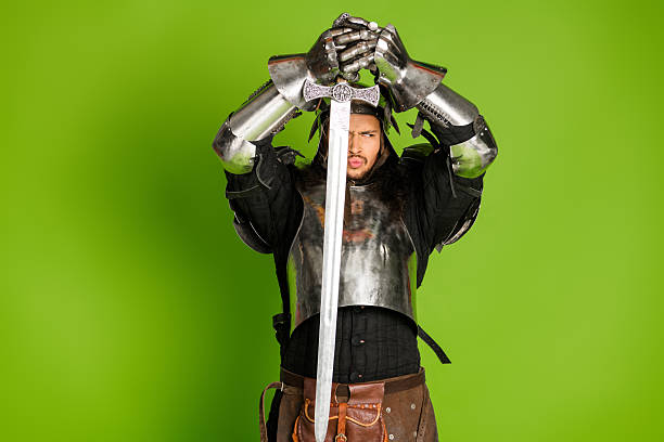 istock Knight in shining armor posing heroically in a medieval style costume with a sword against a vibrant green backdrop 2206804326