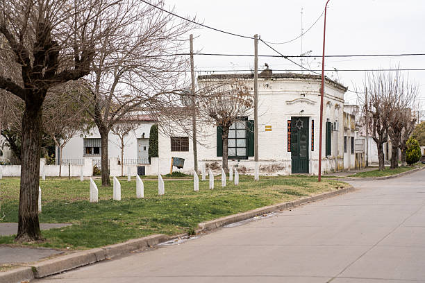 Peaceful street in a small Argentine town with bare winter trees, colonial-style buildings, and a corner store. A calm, nostalgic rural atmosphere.