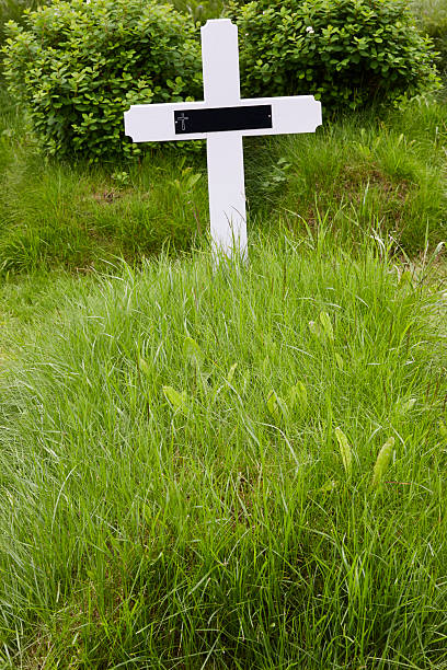istock Catholic white cross over a green grass ground. In memoriam 2206805438
