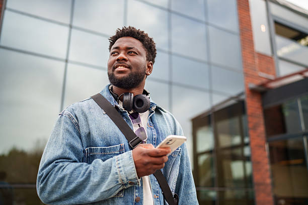 istock Young Black Man Using Smartphone with a Positive Expression on the Street 2206805519