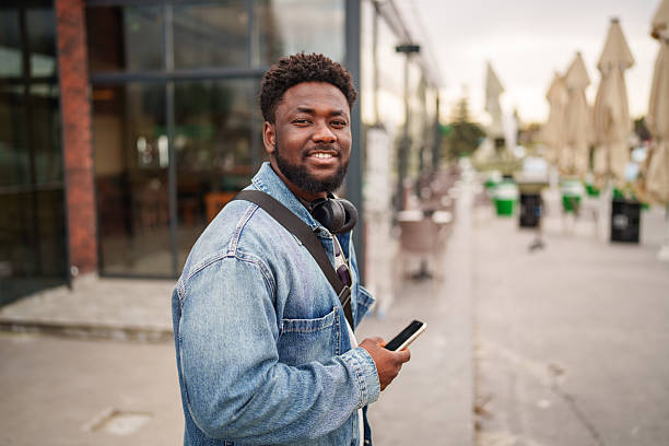 istock Young Black Man Using Smartphone with a Positive Expression on the Street 2206805543