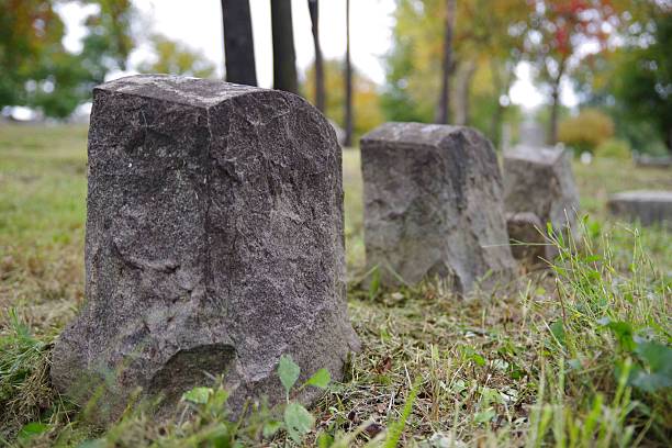 istock Three blank carved ancient gravestones in an old cemetery green grass copy space 2206805647