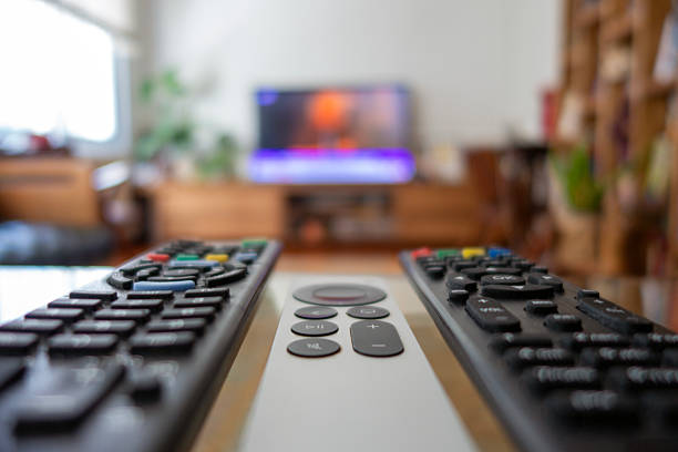 Television control on sofa with defocused television in background.