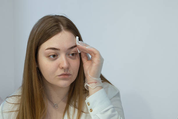istock A young white woman is looking at a mirror, holding a cotton pad for cleaning eyebrows. Self-grooming beauty salon at home concept. Selfcare. 2206806584