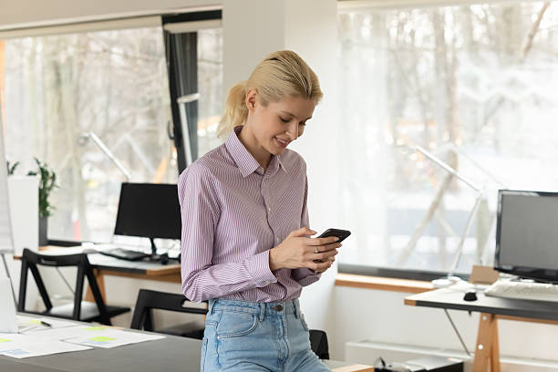 istock Smiling female employee use cellphone texting online 2206811667