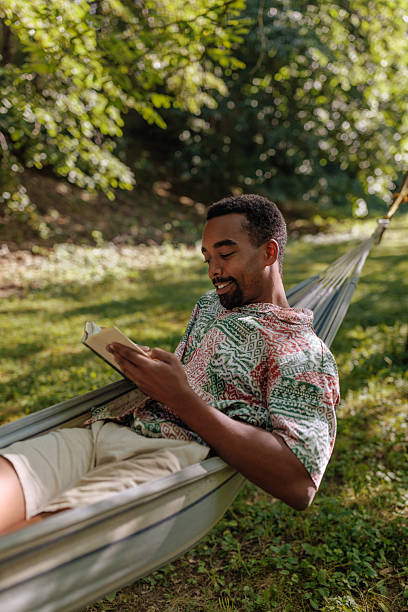 istock Young man relaxing in hammock reading a book in nature 2206813074