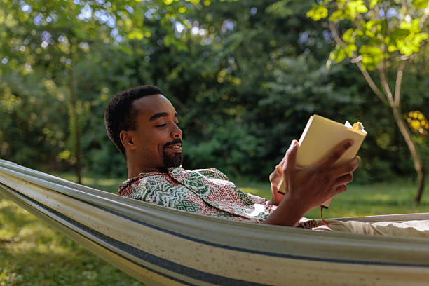 istock Young man relaxing in hammock reading a book in the garden 2206813077