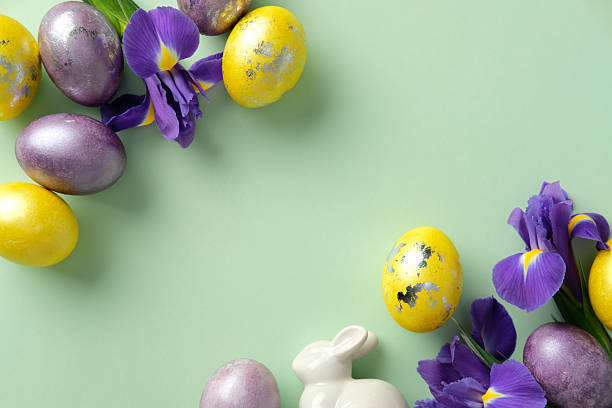 istock Festive Easter composition with colorful eggs, vibrant purple irises, and a white ceramic bunny on a pastel green background 2206814567
