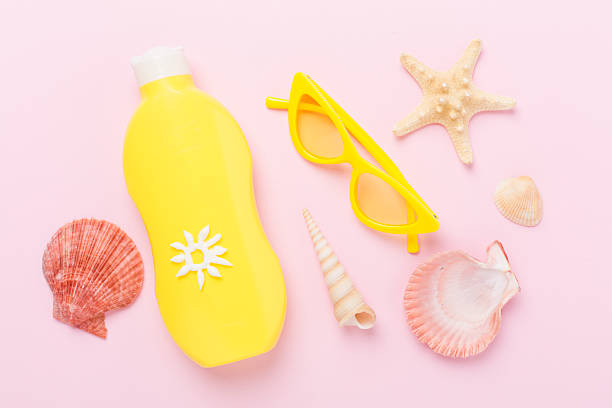 Sunscreen lotion with summer decor on color background, top view
