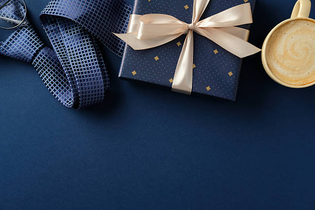 istock Happy Father's day concept. Elegant flat lay composition of a blue gift box, coffee cup, and blue tie on a navy blue background 2206815536