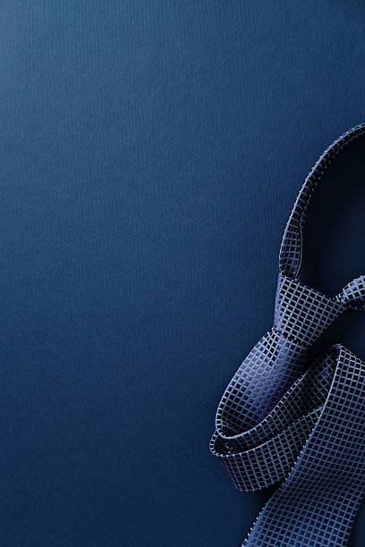 Elegant blue tie with a textured grid pattern on a dark blue background. Happy Father's Day minimalist concept.