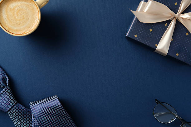 istock Happy Father's day concept. Flat lay composition with gift box, coffee cup, necktie and glasses on navy blue background. 2206815688